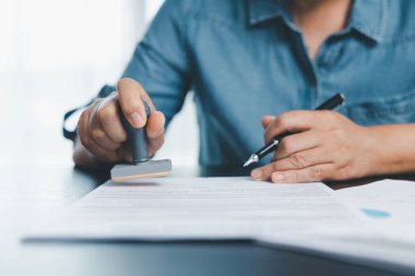 Finans şirketinin onay belgesinde işadamı imzası var. Erkek eli, izin sözleşmesini kabul etti. Komisyoncu yönetici sözleşme banka teminatı onaylı pul başvuru formu imzaladı