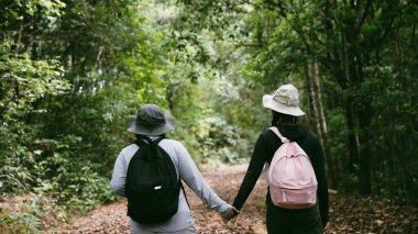 Sırt çantalı iki bayan arkadaş birlikte kırda yürüyüş yapıyorlar. Asyalı arkadaş kız sırt çantalı arkadaş ormanda birlikte seyahat eder. Yürüyüş yaparken mutlu ve güneşli bir gün..