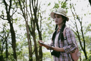 Sırt çantalı genç bir gezgin ulusal parkta ya da ormanda yürüyor. Doğada eğlence sporu. Kadın çantası, ormanda yürüyüş için el sallıyor. Ormanda macera. Sırt çantasıyla yürüyüş