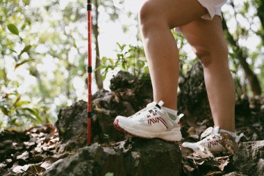 Dağ çim patikasında yürüyüş. Kadın yürüyüşçü ayakkabısını kapat. Yürüyüşçülerin ve sırt çantalarının maceraperest yaşam tarzı seyahat ve dağ yürüyüşleri, her yürüyüşün ve heyecanlı yolculuğun her bölümünün tadını çıkar.