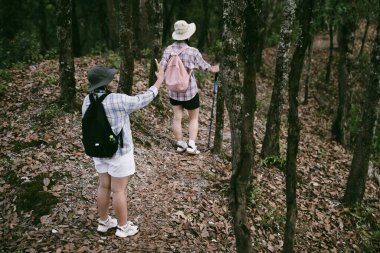 Sırt çantalı iki bayan arkadaş birlikte kırda yürüyüş yapıyorlar. Asyalı arkadaş kız sırt çantalı arkadaş ormanda birlikte seyahat eder. Yürüyüş yaparken mutlu ve güneşli bir gün..