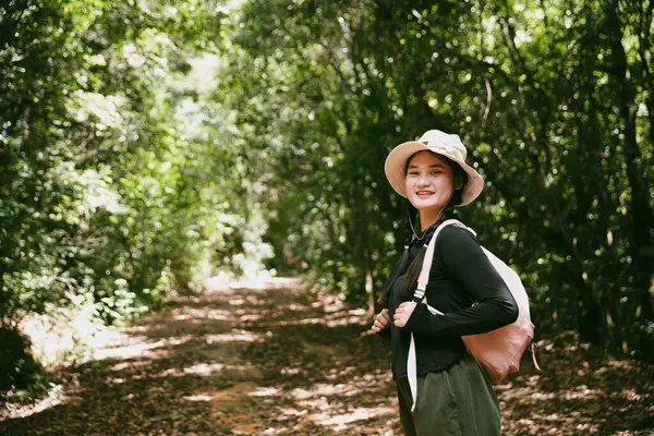 Sırt çantalı genç bir gezgin ulusal parkta ya da ormanda yürüyor. Doğada eğlence sporu. Kadın çantası, ormanda yürüyüş için el sallıyor. Ormanda macera. Sırt çantasıyla yürüyüş
