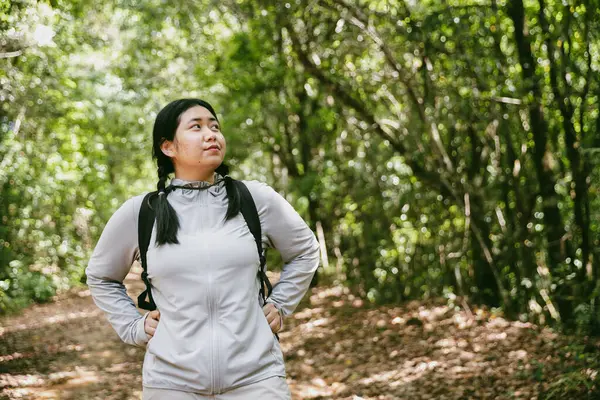 Sırt çantalı genç bir gezgin ulusal parkta ya da ormanda yürüyor. Doğada eğlence sporu. Kadın çantası, ormanda yürüyüş için el sallıyor. Ormanda macera. Sırt çantasıyla yürüyüş