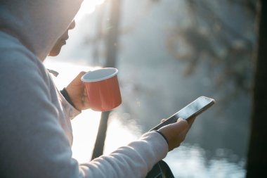 Uzaktan kumanda teknolojisi çevrimiçi iletişim akıllı telefon dizüstü bilgisayar dijital seyahat güneş ışığı kampı içeceği sabah kahve çadırı turuncu dış konsept arka plan iç.