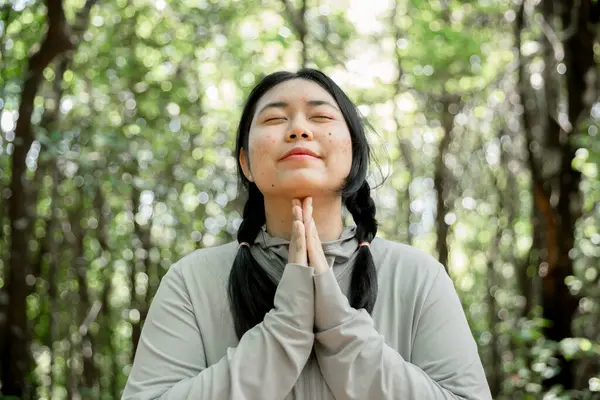 Minnettar bir kadın Tanrı 'ya dua ediyor. Ruhani kız gökyüzüne gülümsüyor. Mutlu bir kadın şükran duyuyor. Ruhsal kız umutla dua ediyor. Pozitif Asyalı genç bir kadın umut ve inanç hissediyor..