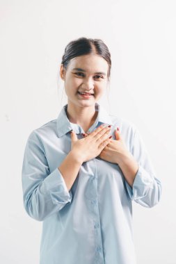 Asyalı bir kadın seviniyor, mutlu görünüyor, şampiyon, yumruk sallıyor, beyaz arka planda duruyor. Genç bir kadının yüzünde mutlu, pozitif bir ifade vardı. Parlak bir gülümsemeyle vurgulanmıştı..