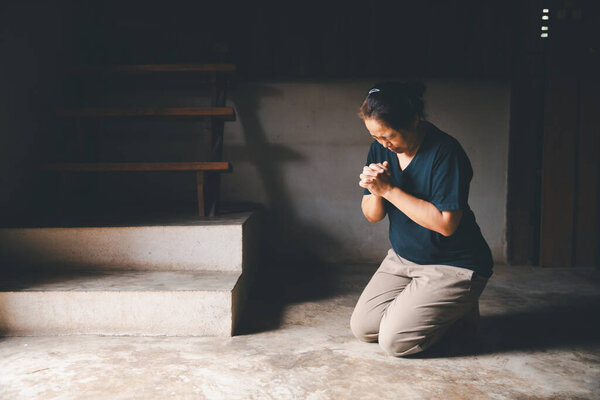 Female kneeling down praying for worship God at home. Christians pray to jesus christ for calmness. people got to quiet place and worship. Christians humble and submit to God. Banner with copy space.