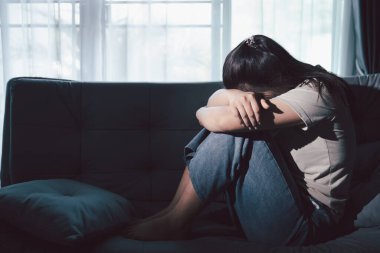 Depresyondaki kadın kanepeye oturur. Kederli insan yalnız başına oturur ve dizlerine sarılır sıkıcı üzgün üzgün sinirli sinirli. Boğucu bir yük altında umut bulmak için mücadele ediyorlar. ruh sağlığı kavramı.