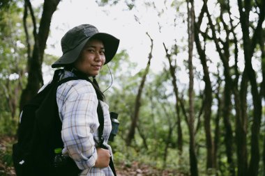 Sırt çantalı genç bir gezgin ulusal parkta ya da ormanda yürüyor. Doğada eğlence sporu. Kadın çantası, ormanda yürüyüş için el sallıyor. Ormanda macera. Sırt çantasıyla yürüyüş