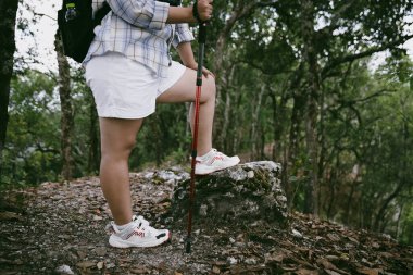 Dağ çim patikasında yürüyüş. Kadın yürüyüşçü ayakkabısını kapat. Yürüyüşçülerin ve sırt çantalarının maceraperest yaşam tarzı seyahat ve dağ yürüyüşleri, her yürüyüşün ve heyecanlı yolculuğun her bölümünün tadını çıkar.