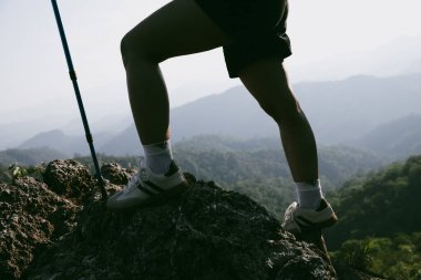Yürüyüş botu. Dağların tepesindeki yürüyüş yolunda botlu kadın bacaklarını kapat. Dağın zirvesine ulaşan genç bir kadın. Kayaların üzerinde yürüyüş botu giyen kadınlar. Seyahat, tatil konsepti.