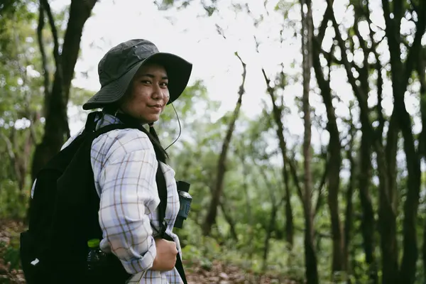 Sırt çantalı genç bir gezgin ulusal parkta ya da ormanda yürüyor. Doğada eğlence sporu. Kadın çantası, ormanda yürüyüş için el sallıyor. Ormanda macera. Sırt çantasıyla yürüyüş