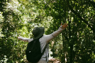 Sırt çantalı genç bir gezgin ulusal parkta ya da ormanda yürüyor. Doğada eğlence sporu. Kadın çantası, ormanda yürüyüş için el sallıyor. Ormanda macera. Sırt çantasıyla yürüyüş