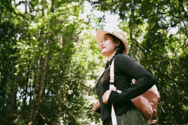 Sırt çantalı genç bir gezgin ulusal parkta ya da ormanda yürüyor. Doğada eğlence sporu. Kadın çantası, ormanda yürüyüş için el sallıyor. Ormanda macera. Sırt çantasıyla yürüyüş