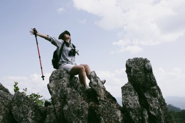 Dağın tepesinde kadın yürüyüşçü. Kolları dağın tepesinde gezen başarılı genç bir kadın zaferin tadını çıkarıyor. Gezgin dünyayı keşfediyor. Sırt çantalı yürüyüşçüler dinleniyor. Spor ve başarı konsepti.