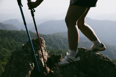 Yürüyüş botu. Dağların tepesindeki yürüyüş yolunda botlu kadın bacaklarını kapat. Dağın zirvesine ulaşan genç bir kadın. Kayaların üzerinde yürüyüş botu giyen kadınlar. Seyahat, tatil konsepti.