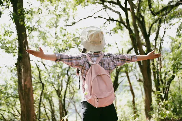 Sırt çantalı genç bir gezgin ulusal parkta ya da ormanda yürüyor. Doğada eğlence sporu. Kadın çantası, ormanda yürüyüş için el sallıyor. Ormanda macera. Sırt çantasıyla yürüyüş
