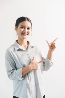 Asyalı bir kadın seviniyor, mutlu görünüyor, şampiyon, yumruk sallıyor, beyaz arka planda duruyor. Genç bir kadının yüzünde mutlu, pozitif bir ifade vardı. Parlak bir gülümsemeyle vurgulanmıştı..