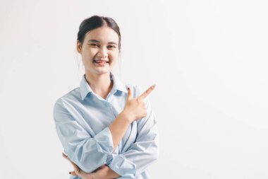 Asyalı bir kadın seviniyor, mutlu görünüyor, şampiyon, yumruk sallıyor, beyaz arka planda duruyor. Genç bir kadının yüzünde mutlu, pozitif bir ifade vardı. Parlak bir gülümsemeyle vurgulanmıştı..