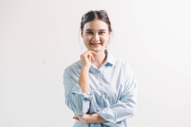 Asyalı bir kadın seviniyor, mutlu görünüyor, şampiyon, yumruk sallıyor, beyaz arka planda duruyor. Genç bir kadının yüzünde mutlu, pozitif bir ifade vardı. Parlak bir gülümsemeyle vurgulanmıştı..