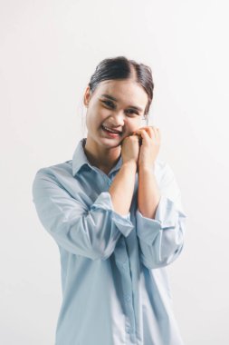 Asyalı bir kadın seviniyor, mutlu görünüyor, şampiyon, yumruk sallıyor, beyaz arka planda duruyor. Genç bir kadının yüzünde mutlu, pozitif bir ifade vardı. Parlak bir gülümsemeyle vurgulanmıştı..