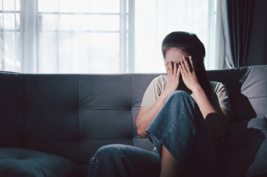 Depresyondaki kadın kanepeye oturur. Kederli insan yalnız başına oturur ve dizlerine sarılır sıkıcı üzgün üzgün sinirli sinirli. Boğucu bir yük altında umut bulmak için mücadele ediyorlar. ruh sağlığı kavramı.