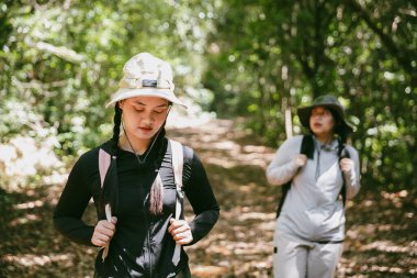 Sırt çantalı iki bayan arkadaş birlikte kırda yürüyüş yapıyorlar. Asyalı arkadaş kız sırt çantalı arkadaş ormanda birlikte seyahat eder. Yürüyüş yaparken mutlu ve güneşli bir gün..