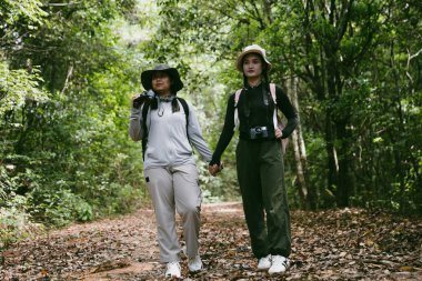 Sırt çantalı iki bayan arkadaş birlikte kırda yürüyüş yapıyorlar. Asyalı arkadaş kız sırt çantalı arkadaş ormanda birlikte seyahat eder. Yürüyüş yaparken mutlu ve güneşli bir gün..