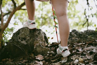 Dağ çim patikasında yürüyüş. Kadın yürüyüşçü ayakkabısını kapat. Yürüyüşçülerin ve sırt çantalarının maceraperest yaşam tarzı seyahat ve dağ yürüyüşleri, her yürüyüşün ve heyecanlı yolculuğun her bölümünün tadını çıkar.