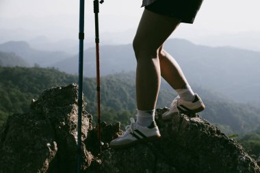 Yürüyüş botu. Dağların tepesindeki yürüyüş yolunda botlu kadın bacaklarını kapat. Dağın zirvesine ulaşan genç bir kadın. Kayaların üzerinde yürüyüş botu giyen kadınlar. Seyahat, tatil konsepti.