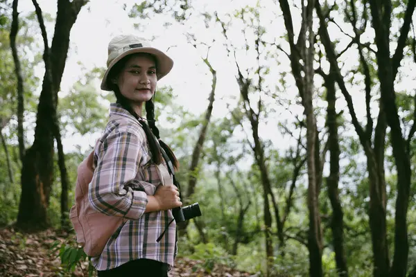 Sırt çantalı genç bir gezgin ulusal parkta ya da ormanda yürüyor. Doğada eğlence sporu. Kadın çantası, ormanda yürüyüş için el sallıyor. Ormanda macera. Sırt çantasıyla yürüyüş