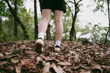 Dağ çim patikasında yürüyüş. Kadın yürüyüşçü ayakkabısını kapat. Yürüyüşçülerin ve sırt çantalarının maceraperest yaşam tarzı seyahat ve dağ yürüyüşleri, her yürüyüşün ve heyecanlı yolculuğun her bölümünün tadını çıkar.