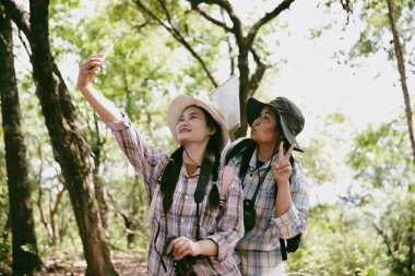Sırt çantalı iki bayan arkadaş birlikte kırda yürüyüş yapıyorlar. Asyalı arkadaş kız sırt çantalı arkadaş ormanda birlikte seyahat eder. Yürüyüş yaparken mutlu ve güneşli bir gün..