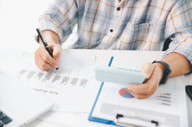 Ofisteki finans raporunu hesaplamak için hesap makinesi kullanan bir muhasebeci. işletme finansmanı, mali belgeleri düzenleyerek vergi hesaplama, gelir yatırımlarını takip etme, elle hesaplama.