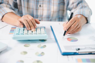 Ofisteki finans raporunu hesaplamak için hesap makinesi kullanan bir muhasebeci. işletme finansmanı, mali belgeleri düzenleyerek vergi hesaplama, gelir yatırımlarını takip etme, elle hesaplama.