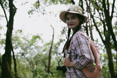 Sırt çantalı genç bir gezgin ulusal parkta ya da ormanda yürüyor. Doğada eğlence sporu. Kadın çantası, ormanda yürüyüş için el sallıyor. Ormanda macera. Sırt çantasıyla yürüyüş