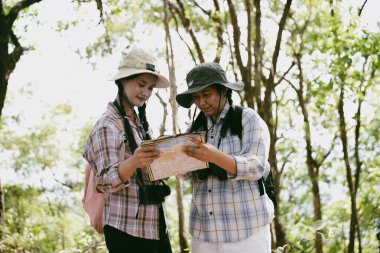 Sırt çantalı iki bayan arkadaş birlikte kırda yürüyüş yapıyorlar. Asyalı arkadaş kız sırt çantalı arkadaş ormanda birlikte seyahat eder. Yürüyüş yaparken mutlu ve güneşli bir gün..