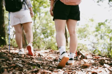 Dağ çim patikasında yürüyüş. Kadın yürüyüşçü ayakkabısını kapat. Yürüyüşçülerin ve sırt çantalarının maceraperest yaşam tarzı seyahat ve dağ yürüyüşleri, her yürüyüşün ve heyecanlı yolculuğun her bölümünün tadını çıkar.