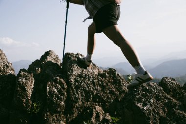 Yürüyüş botu. Dağların tepesindeki yürüyüş yolunda botlu kadın bacaklarını kapat. Dağın zirvesine ulaşan genç bir kadın. Kayaların üzerinde yürüyüş botu giyen kadınlar. Seyahat, tatil konsepti.