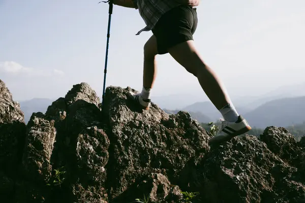 Yürüyüş botu. Dağların tepesindeki yürüyüş yolunda botlu kadın bacaklarını kapat. Dağın zirvesine ulaşan genç bir kadın. Kayaların üzerinde yürüyüş botu giyen kadınlar. Seyahat, tatil konsepti.