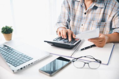 Ofisteki finans raporunu hesaplamak için hesap makinesi kullanan bir muhasebeci. işletme finansmanı, mali belgeleri düzenleyerek vergi hesaplama, gelir yatırımlarını takip etme, elle hesaplama.