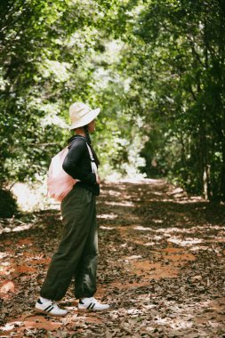 Sırt çantalı genç bir gezgin ulusal parkta ya da ormanda yürüyor. Doğada eğlence sporu. Kadın çantası, ormanda yürüyüş için el sallıyor. Ormanda macera. Sırt çantasıyla yürüyüş