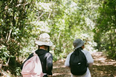 Sırt çantalı iki bayan arkadaş birlikte kırda yürüyüş yapıyorlar. Asyalı arkadaş kız sırt çantalı arkadaş ormanda birlikte seyahat eder. Yürüyüş yaparken mutlu ve güneşli bir gün..