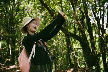 Sırt çantalı genç bir gezgin ulusal parkta ya da ormanda yürüyor. Doğada eğlence sporu. Kadın çantası, ormanda yürüyüş için el sallıyor. Ormanda macera. Sırt çantasıyla yürüyüş