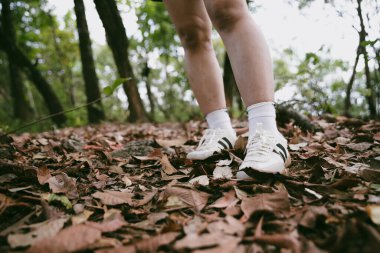 Dağ çim patikasında yürüyüş. Kadın yürüyüşçü ayakkabısını kapat. Yürüyüşçülerin ve sırt çantalarının maceraperest yaşam tarzı seyahat ve dağ yürüyüşleri, her yürüyüşün ve heyecanlı yolculuğun her bölümünün tadını çıkar.