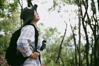 Sırt çantalı genç bir gezgin ulusal parkta ya da ormanda yürüyor. Doğada eğlence sporu. Kadın çantası, ormanda yürüyüş için el sallıyor. Ormanda macera. Sırt çantasıyla yürüyüş