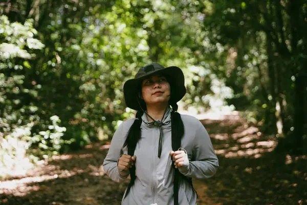 Sırt çantalı genç bir gezgin ulusal parkta ya da ormanda yürüyor. Doğada eğlence sporu. Kadın çantası, ormanda yürüyüş için el sallıyor. Ormanda macera. Sırt çantasıyla yürüyüş