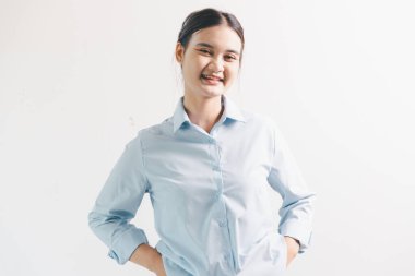 Asyalı bir kadın seviniyor, mutlu görünüyor, şampiyon, yumruk sallıyor, beyaz arka planda duruyor. Genç bir kadının yüzünde mutlu, pozitif bir ifade vardı. Parlak bir gülümsemeyle vurgulanmıştı..