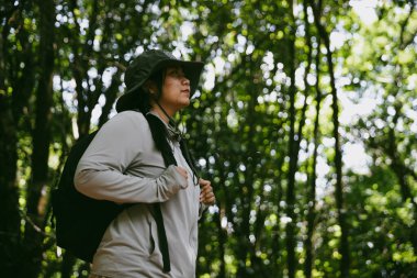 Sırt çantalı genç bir gezgin ulusal parkta ya da ormanda yürüyor. Doğada eğlence sporu. Kadın çantası, ormanda yürüyüş için el sallıyor. Ormanda macera. Sırt çantasıyla yürüyüş