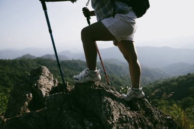 Yürüyüş botu. Dağların tepesindeki yürüyüş yolunda botlu kadın bacaklarını kapat. Dağın zirvesine ulaşan genç bir kadın. Kayaların üzerinde yürüyüş botu giyen kadınlar. Seyahat, tatil konsepti.
